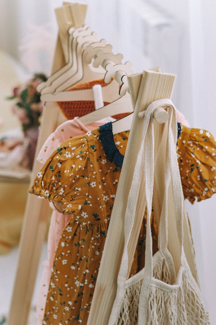 Wooden hangers displaying colorful children's dresses in a boutique setting.